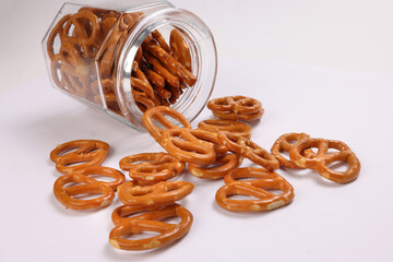 Pretzel cracker in a glass jar pouring dropping on white background