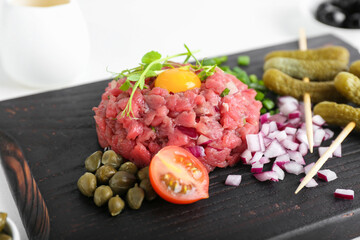 Board with tasty beef tartare on light background, closeup