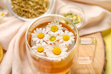 Composition with cup of chamomile tea and flowers on table, closeup