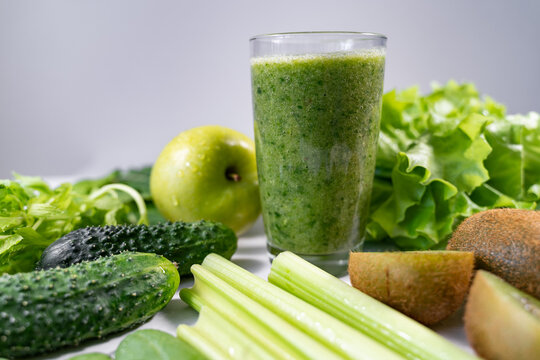 A healthy smoothie made from celery, kiwi, green apples and cucumbers stands on a white table. Vegetarian food. Diet breakfast.