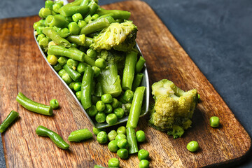Scoop with frozen green vegetables on dark background, closeup