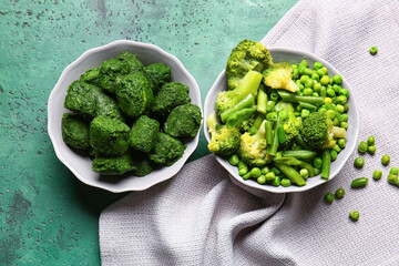 Bowls with frozen green vegetables on color background