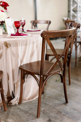 Decorating a wedding table with red and pink flowers using rustic wooden chairs.
