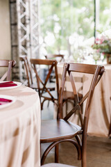 Decorating a wedding table with red and pink flowers using rustic wooden chairs.