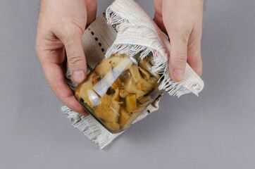 A glass jar with homemade pickled mushrooms against a gray backg