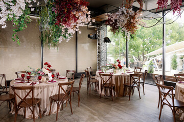 Elegant festive wedding decor with vintage wood chairs, powdery tablecloths and hanging flowers and foliage from the ceiling.