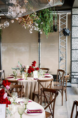 Restaurant wedding decor with red glasses and purple flowers. Vintage wooden chairs