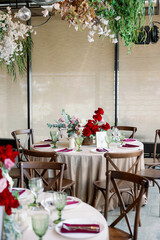 Elegant festive wedding decor with vintage wood chairs, powdery tablecloths and hanging flowers and foliage from the ceiling.