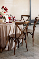 Restaurant wedding decor with red glasses and purple flowers. Vintage wooden chairs