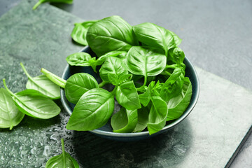 Bowl with fresh basil leaves on table, closeup