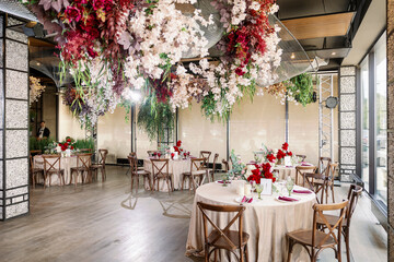 Restaurant wedding decor with red glasses and purple flowers. Vintage wooden chairs