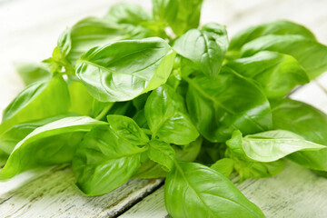 Fresh basil leaves on light wooden background, closeup