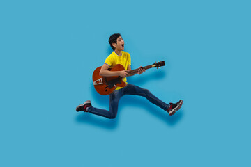 AN EXCITED TEENAGER PLAYING GUITAR WHILE JUMPING
