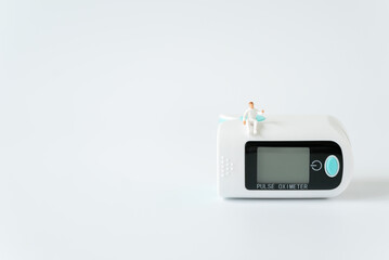 Miniature people doctor sitting on oxygen level modern fingertip pulse oximeter on white background...