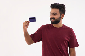 A BEARDED YOUNG MAN LOOKING AT DEBIT CARD IN HAND