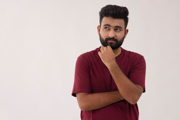 A YOUNG BEARDED MAN STANDING AND THINKING