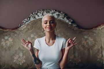 Millenial young woman with short blonde hair portrait sitting and meditate with ok sign mudra on...