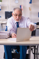 Old male employee in wheel-chair sitting in the office
