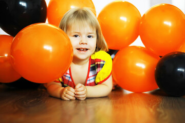 Fototapeta na wymiar Portrait of a small child lying on the floor in a room decorated with balloons. Happy childhood concept.