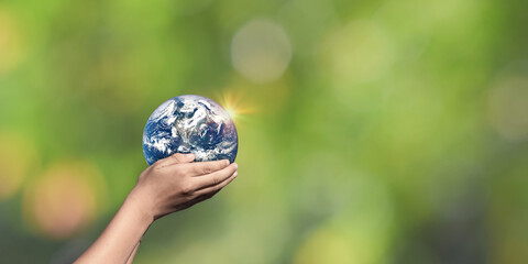 Hands holding Globe, Earth on green nature background. Elements of this image furnished by NASA