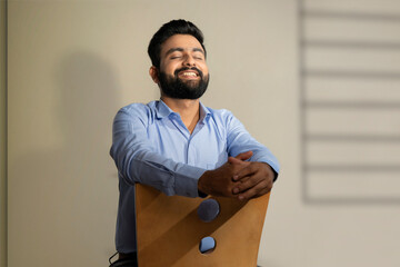 A HAPPY BEARDED MAN SITTING AND FEELING HAPPY