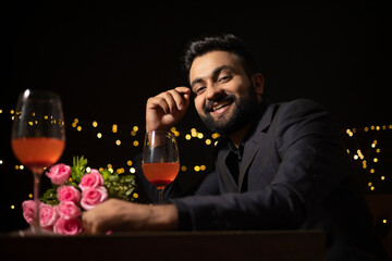 A SMART BEARDED MAN LOOKING AT CAMERA WHILE ATTENDING PARTY