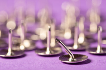 Group of sharp push pins with one crooked and unable to hold something on the foreground....