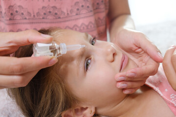 close up mother drips in eyes of the girl a medicinal solution