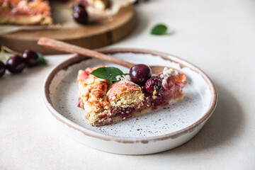 Piece of open pie or galette with cherry, almond and vanilla ice cream, light background.