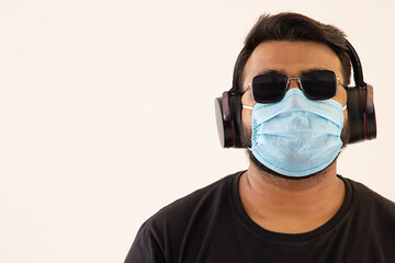 Portrait of a young man with headphones and mask on his face.