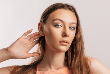Naklejka premium Beautiful young girl holds his hand near his ear, wants to hear better on a white background with a place for advertising mockup