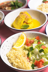 Bulgur with vegetables in a plate with other dishes on table. Delicious healthy dish in a bowl