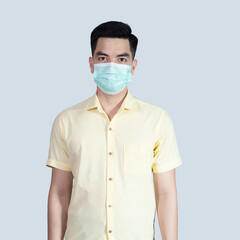 COVID-19 Coronavirus portrait handsome young asian .man wearing yellow shirt and mask protection from covid 19 isolated on grey background in studio. Asian man people. COVID-19 concept.