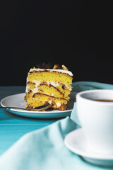 Cappuccino coffee in a cup and pistachio cake, sponge cake with nuts decoration over black background.