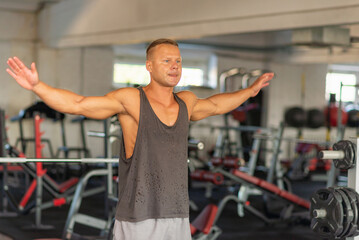 Fototapeta na wymiar Fitness man warming up in gym. Male doing warm up stretching workout on gym background.