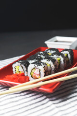 Tasty and fresh sushi set served in a red plate with wooden chopsticks. Close-up, selective focus on sushi.
