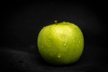 Fototapeta na wymiar Wet Green Apple on Black Background