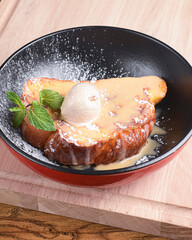 Freshly baked deep dish apple pie with ice cream and sweet sauce. Served in a bowl over wooden background.