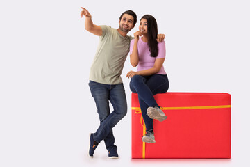 Fototapeta premium A young man showing something to the woman sitting on gift shaped stool beside him.