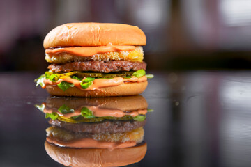 Big chicken and beef burger on reflected surface. Juicy hamburger over blurred background.