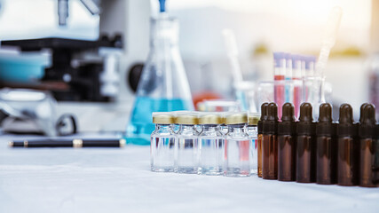 medical or scientific researcher researching and experimenting Multi-colored solution, vial and microscope In the laboratory or in the laboratory by wearing blue gloves and white clothing completely.