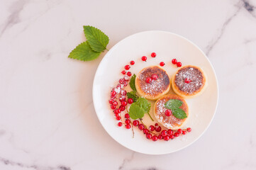 Cottage cheese pancakes, syrniki, curd fritters with fresh berries of red currant in a white plate. Gourmet Breakfast. Selective focus