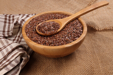 Flex seed flaxseed in wooden bowl spoon on jute fabric cloths