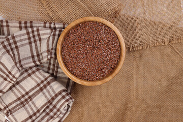 Flex seed flaxseed in wooden bowl on jute fabric cloths top view