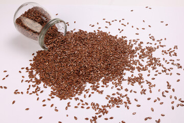 Flex seed flaxseed closeup pouring from small glass jar bottle sprinkled seeds