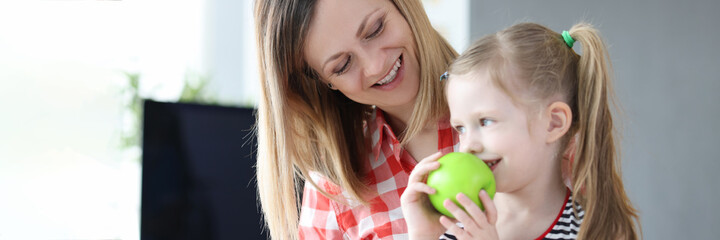 Fototapeta premium Woman has little girl on her lap and has apple