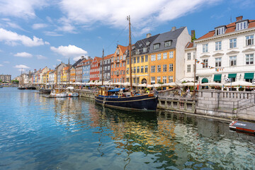 Panorama view of Nyhawn, the colorful houses next to the old port. Tourist visiting restaurants, cafes and ships in the canal. The most important sightseeing spot in Copenhagen, Denmark.