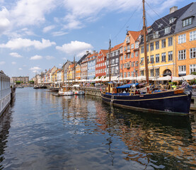 Panorama view of Nyhawn, the colorful houses next to the old port. Tourist visiting restaurants, cafes and ships in the canal. The most important sightseeing spot in Copenhagen, Denmark.