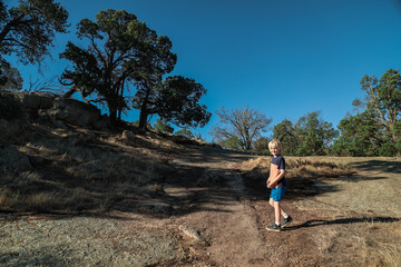 Boy exploring rocky hill top at the Terrick Terrick National Park near Mitiamo, Victoria Australia