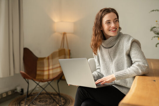Young woman working on a laptop looking aside with a grin